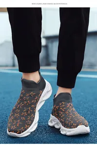Dettagli della scarpa sportiva grigia in maglia con stelle arancioni su pista blu