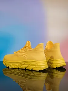 Nahaufnahme gelber Fly-Knit Wanderschuh mit dicker rutschfester Sohle vor Farbverlauf-Hintergrund