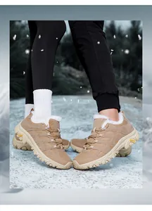 Detail von khakifarbenen Winter-Wanderschuhen mit warmem Lammfellfutter auf dem Schnee