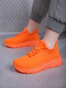 Tragefoto der leuchtend orangefarbenen Wanderschuhe aus atmungsaktivem Mesh mit dicker Sohle