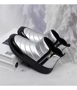 Detail of silver metallic snow boot with black patent leather trim and side zipper