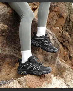 Close-up of black hiking shoes with toggle laces and outdoor rubber sole on rocks