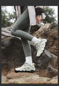 On-foot view of beige outdoor hiking shoes with thick black rubber soles for rugged terrain