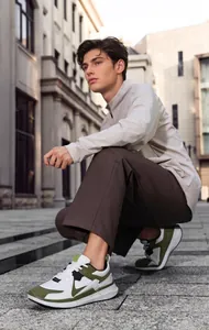 Outdoor shot of men's retro thick-sole sneakers with green and white stitching details