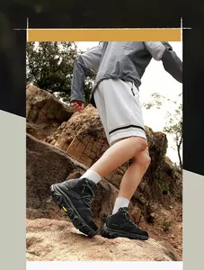 Close-up of black breathable outdoor hiking boots featuring non-slip soles on rocky terrain