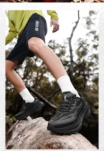 Close-up of black breathable outdoor sneakers with thick cushioning sole on rocks