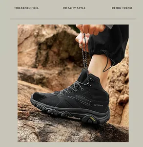 Detail of a hiker tying black outdoor trekking boots with a thick rubber sole on rocky terrain