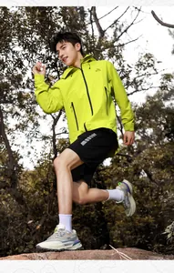 Outdoor athlete in neon green hooded jacket and sports shorts during trail hiking