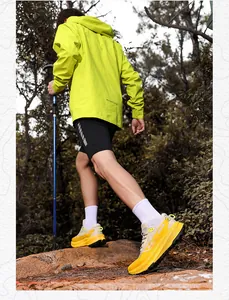 Outdoor hiker in neon jacket and yellow trekking shoes climbing with trekking pole
