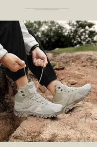 Action shot showing the lacing of khaki high-top hiking boots on rugged terrain
