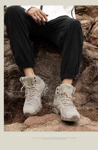 Close-up of khaki outdoor hiking boots with mesh and suede texture on a rocky terrain