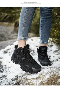 Close-up of black waterproof hiking boots on snow with durable anti-slip rubber soles