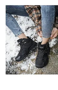 Detail of grey outdoor hiking boots with anti-slip soles on a snow-covered rocky ground