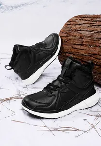 Close-up of black high-top winter boots with warm faux fur lining on snowy ground