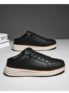 Detail view of black leather mule shoes with thick white soles and orange accent lines