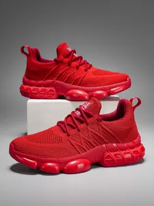 Detail of red flyknit running shoes with cushioning rubber soles on a grey background