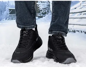 Close-up of black waterproof outdoor winter boots with thick rubber soles on snow