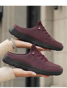 Detail view of burgundy slip-on mule sneakers with thick black sole and gold buckle