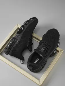 Λεπτομερής προβολή των μαύρων sneakers με πλέγμα και παχιά σόλα με αντικραδασμική προστασία