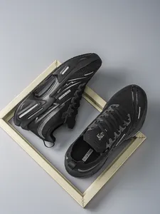 Vista superior de zapatillas de correr negras transpirables con malla sobre fondo gris