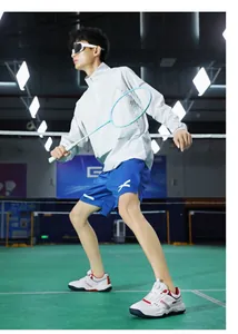 Full view of white and red badminton shoes paired with gray top and blue shorts on court