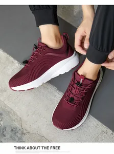 Draufsicht auf weinrote Strick-Laufschuhe mit elastischen Schnürsenkeln auf einem Betonboden