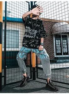Tenue street pour homme avec t-shirt noir graffiti, jean gris et baskets en mesh