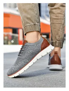 Macro detail of grey breathable flyknit fabric and brown leather trim on a men's sneaker