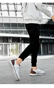 Close-up of white breathable fly-knit men's sneakers with brown leather heel detail
