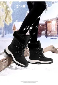 Nahaufnahme schwarzer Schneestiefel mit Steppmuster, Kunstfellbesatz und EVA-Sohle im Schnee