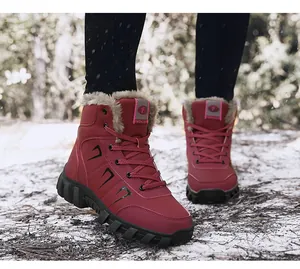 Close-up of red winter snow boots with thick faux fur lining on a snowy forest background