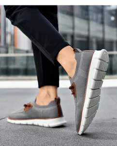 Close-up of grey knit slip-on sneaker featuring brown leather accents and a thick white sole