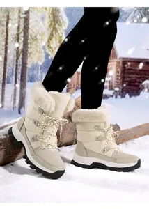 Nahaufnahme gesteppter Winterstiefel mit weißem Kunstfellfutter in einer Schneelandschaft