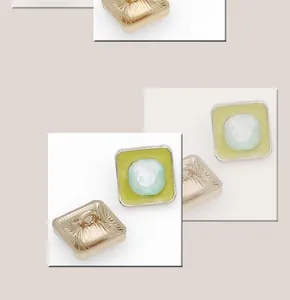 Macro shot of rectangular gold metal button with blue gem and green enamel details