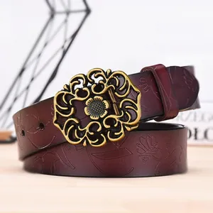 Detail of vintage embossed leather belt with ornate floral buckle and wine red pattern