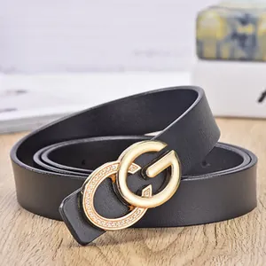 Close-up of black leather belt with gold-tone CG buckle featuring embedded crystals