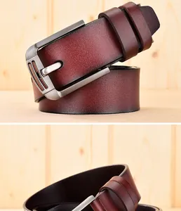 Détail de ceinture en cuir marron rouge vintage avec boucle en métal brossé sur bois