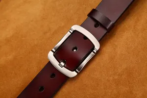 Dettaglio di una cintura in pelle marrone scuro con fibbia in metallo spazzolato e cuciture