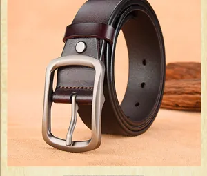 Macro detail of men's dark brown leather belt with matte silver pin buckle texture