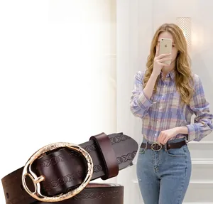 Close-up of embossed dark brown leather belt for women with a gold oval metal buckle