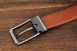 Macro detail of brown textured leather belt with a dark metallic needle buckle on wood