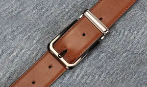 Detail of brown leather belt with metal pin buckle on denim fabric background