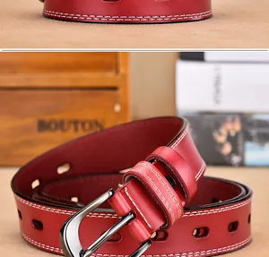 Detail of red leather belt with double white stitching and metal pin buckle