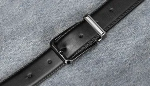 Macro detail of men's black leather belt with silver pin buckle on denim fabric