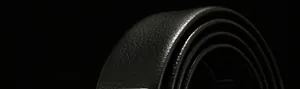 Detail shot of black faux leather belt showing realistic lychee texture and smooth edges
