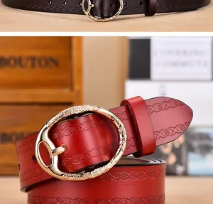 Close-up of embossed floral leather belt with engraved golden oval buckle