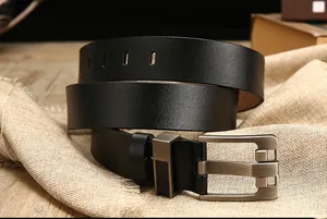 Detalle de cinturón de cuero negro con hebilla de metal oscuro sobre madera rústica