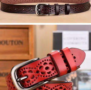 Dettaglio di cinture in pelle traforata con fibbie metalliche e motivi floreali tagliati al laser