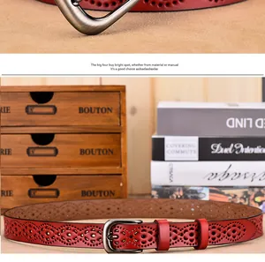 Dettaglio cintura in pelle rosso scuro con motivi floreali traforati e fibbia in argento