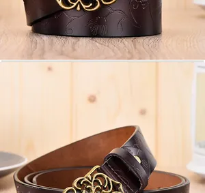 Détail d'une ceinture en cuir marron foncé avec motif floral et boucle dorée